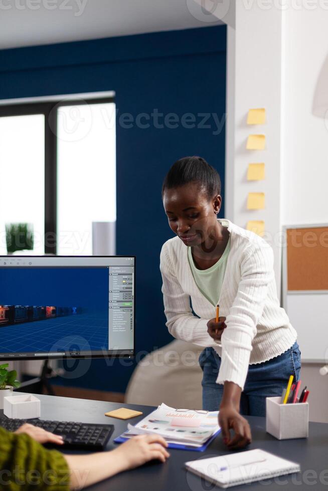 Multiethnic women designer looking at computer with dual displays working together at gaming project in startup office. Gamer workers developing digital games on pc with modern technology photo