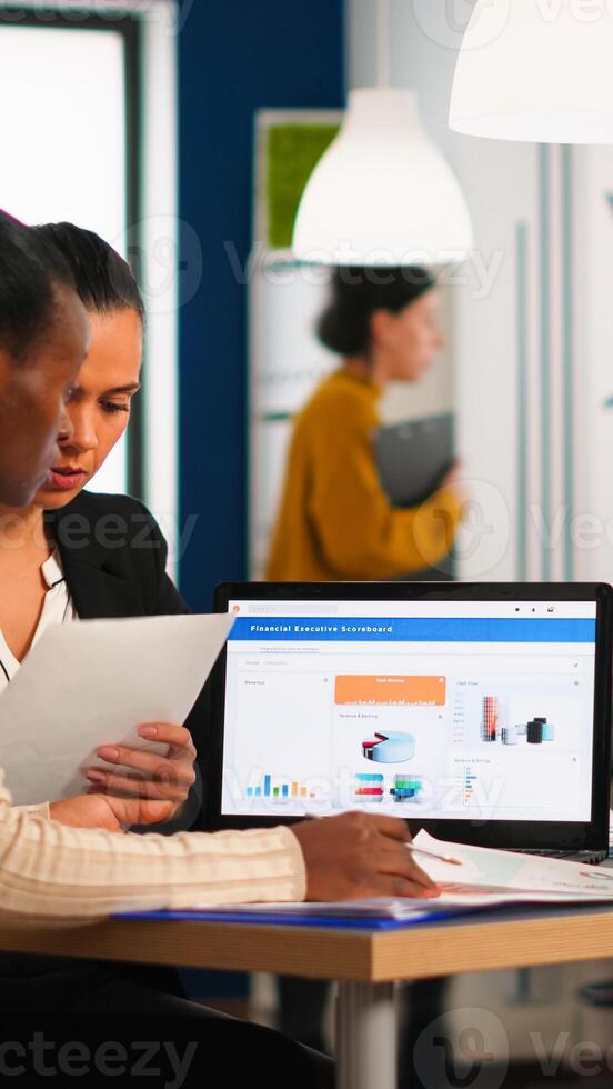 Diverse business people, company staff group, sitting at desk in modern office, discussing about financial problems sitting at desk working on laptop computer in corporate workplace. photo