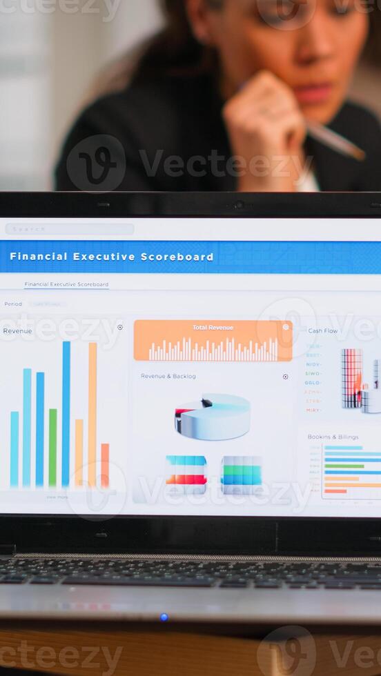 Laptop screen ready for financial project presentation placed on desk while business people work in background. Diverse employees gathered in co-working, working process in busy company, teamwork help photo