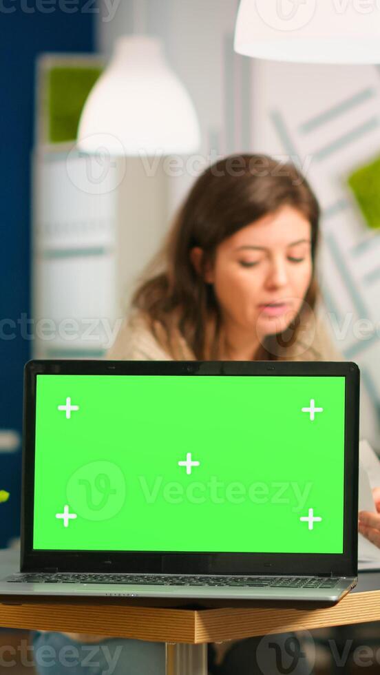 Group of business people discussing company plan with mockup laptop in front of camera, pc ready for financial project presentation placed on desk. Leader using green screen pc with chroma key display photo