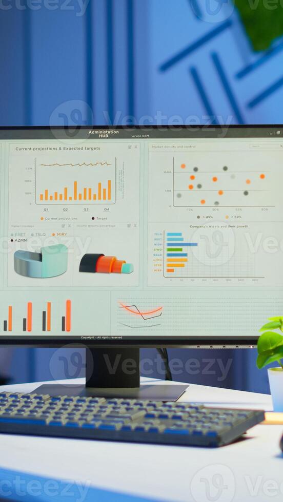 Interior of empty start up business office with modern design during night with graphics running on the desktop. Financial company with nobody in it, place of work startup, workplace indoors concept photo