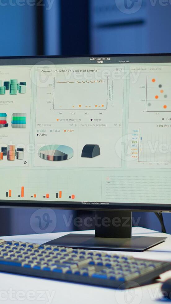 Financial company with nobody in it, place of work startup, workplace indoors concept. Interior of empty start up business office with modern design during night with graphics running on the desktop. photo