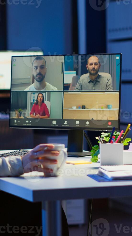 Employee working overtime from business office late at night discussing with partners online using webcam. Corporate meeting using technology network wireless discussing on webcam late at night photo
