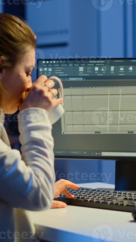 Freelancer architect working in 3D software to elaborate container design sitting at desk in business office at midnight. Focused engineer creating and studying prototype, analysing scale model. photo