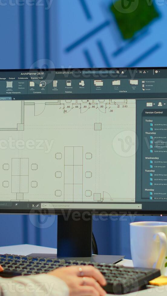 Over the shoulder shot of engineer working with architectural plans, cad software on desktop computer. Designer using arhitecture blueprints of buildings working overtime, creating and studying photo