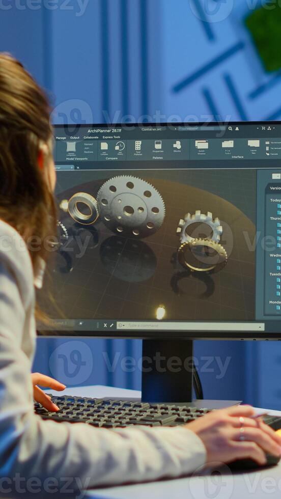 Woman architect working in modern cad program overtime sitting at desk in start-up business office. Industrial employee studying prototype idea on computer showing cad software on device display photo