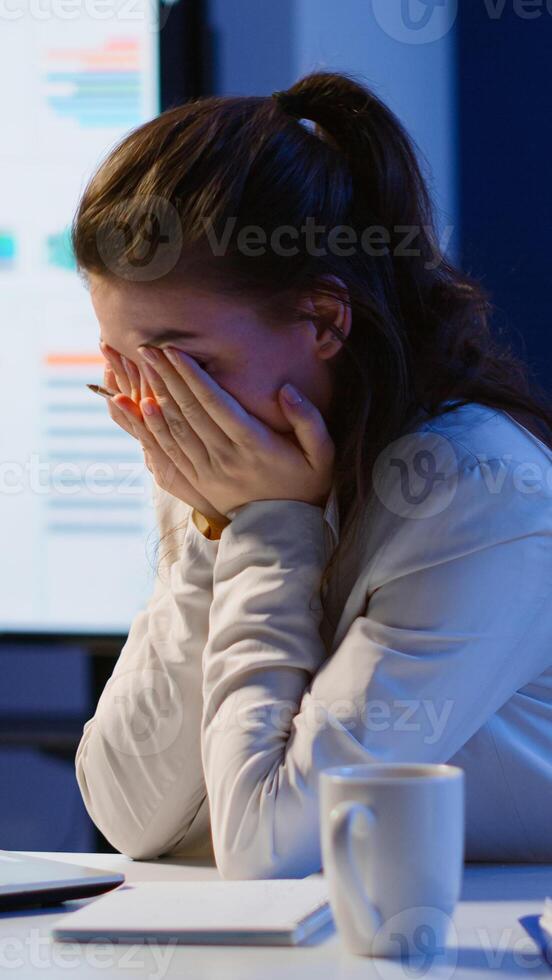 Exhausted freelancer sleeping in front of laptop working in modern start up company office late at night. Stressed employee using modern technology network wireless doing overtime closing eyes. photo