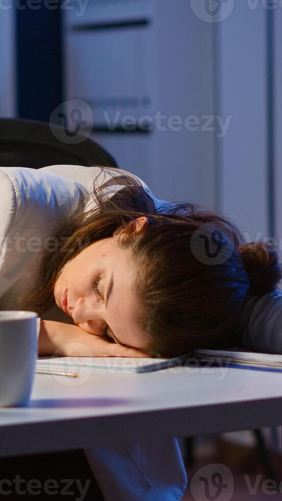 Exhausted overload business woman falling asleep on desk with open laptop monitor while working in start up company office. Employee using modern technology network wireless doing overtime sleeping photo