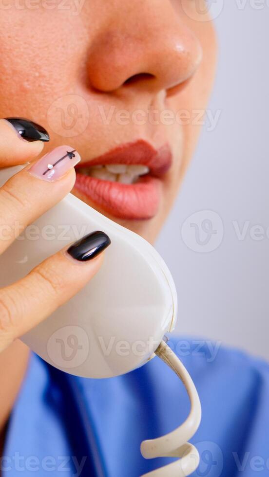 Close up of medical receptionist answering phone calls from patient in hospital making appointment. Healthcare physician in medicine uniform, doctor assistant helping with telehealth communication photo