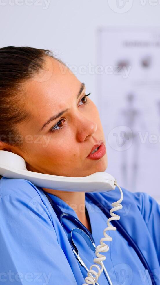 Close up of assistant answering phone checking the result of patient x-ray and diagnosing him. Healthcare physician in medicine uniform, receptionist doctor nurse helping with telephone concultation photo
