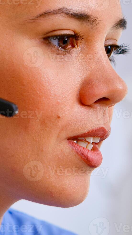 Close up of medical operator with headphone consulting patients during telehealth discussion in hospital. Healthcare physician in medicine uniform, doctor nurse assistent helping with appointment photo
