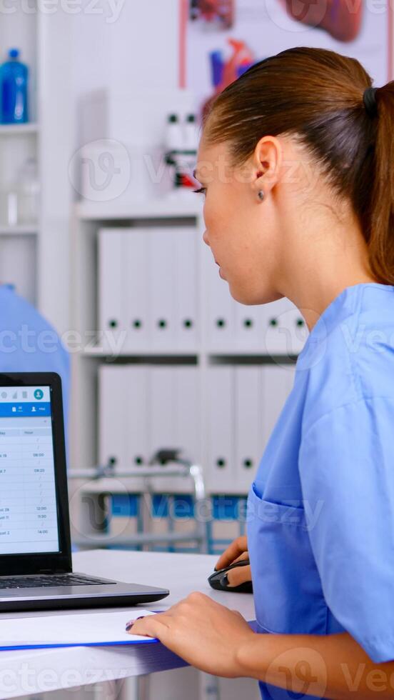 Doctor assistant checking list diagnosed of patients, writing on clipboard with x-ray and medical equipment around. Physician working in hospital making appointments and analysing patient registration photo