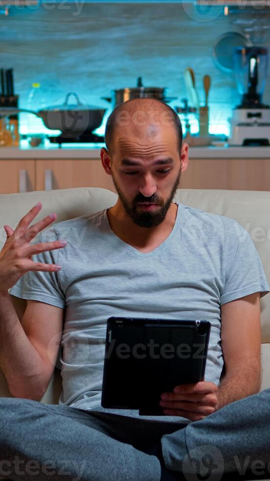 Focused man having online meeting videocall on tablet computer speaking using videoconference online web internet communication. Caucasian man browsing on internet for deadline project photo