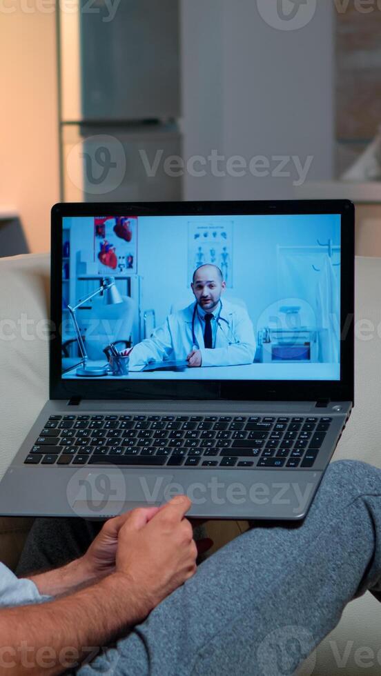 Sick man having online telemedicine consultation during covid-19. Caucasian male sitting in front of laptop disscusing with medical physician about illness symptoms working on healthcare treatment photo
