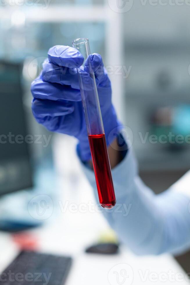 Closeup of biologist chemist holding medical test tube with blood developing virus treatment during biochemistry experiment. Scientist doctor working at healthcare treatment in clinical laboratory photo