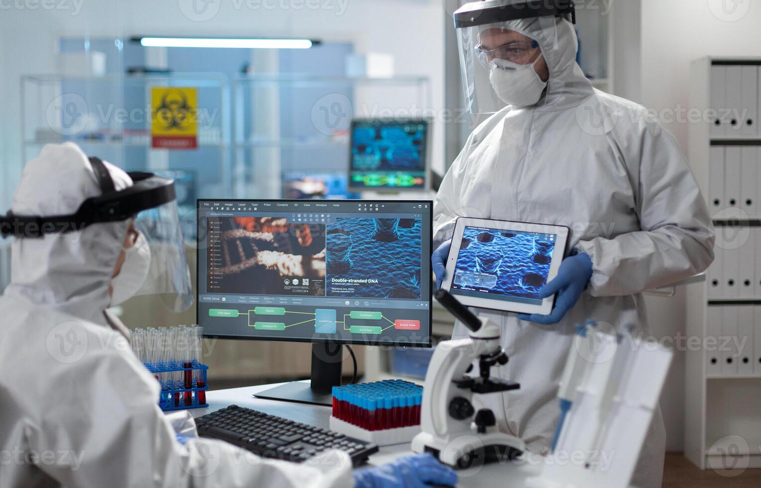 Medical team of scientist analyzing covid19 vaccine development expertise using tablet during clinical investigation in hospital laboratory. Biologist researchers wearing ppe suit against virus photo