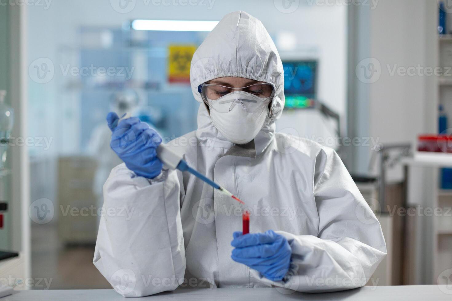 Scientist woman analyzing blood using medical micropippete during covid19 vaccine development working in microbiological hospital laboratory. Researcher wearing ppe suit during clinical experiment photo