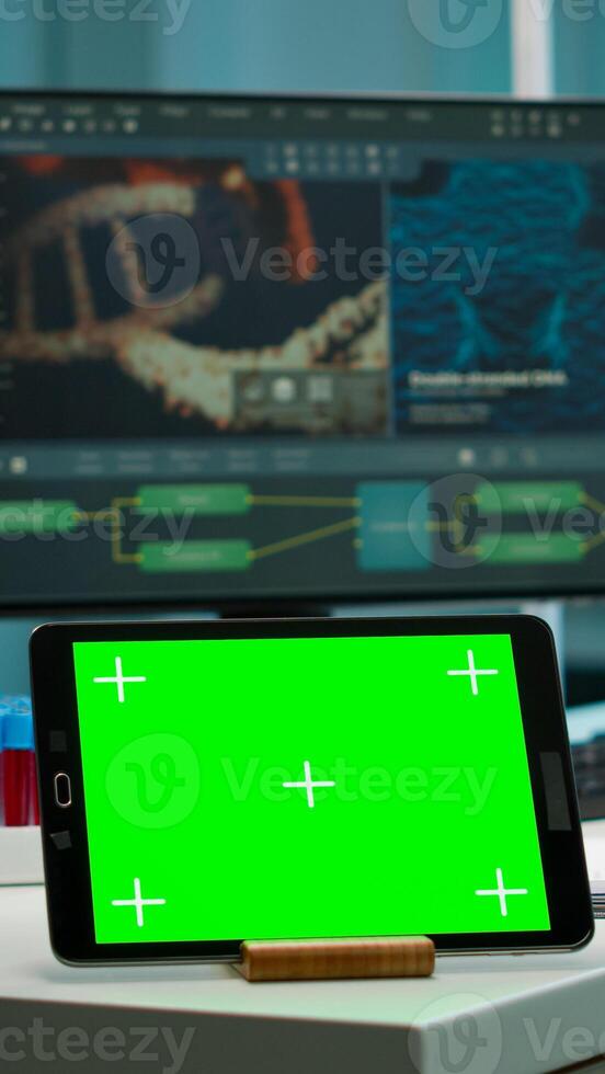 Display tablet with green screen, mock up on template placed on desk in scientific laboratory while woman medical research scientist analysing virus evolution at digital monitor conducting experiment photo