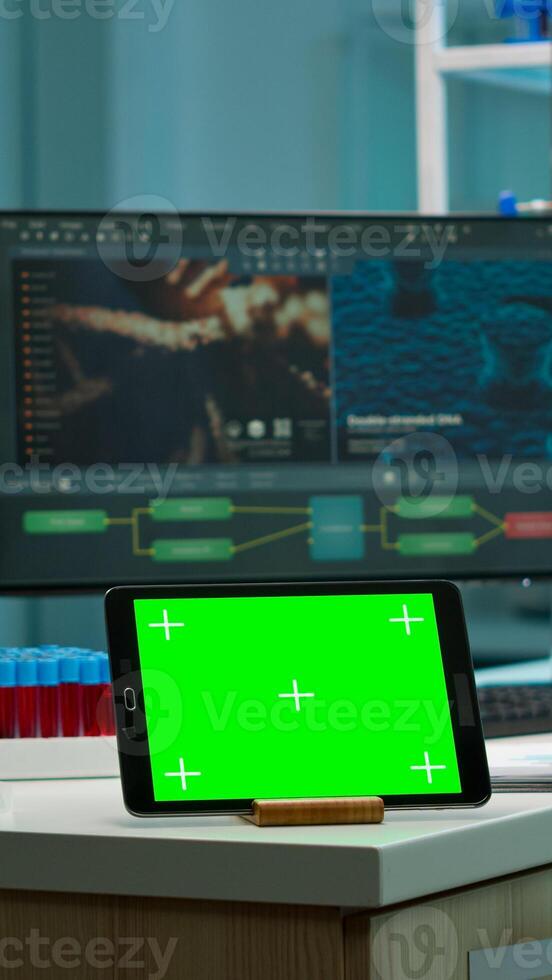 Notepad with green screen working in labooratory with mock up monitor, chroma key display while professional engineer testing virus evolution in background. High tech development lab. photo