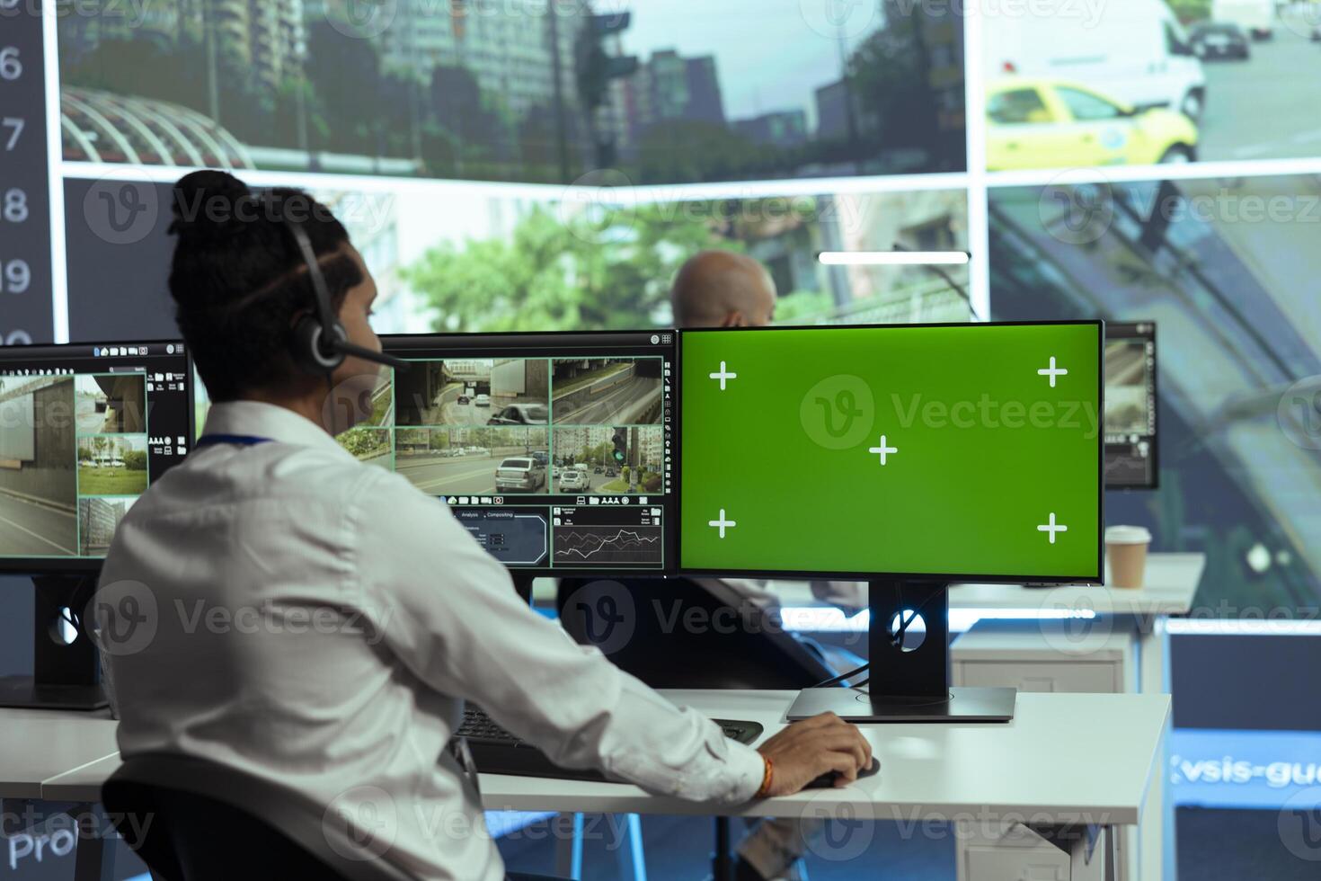 Indian employee gather intelligence on urban traffic activity next to isolated mockup screen, working in monitoring room with CCTV street surveillance footage. Real time radar . photo