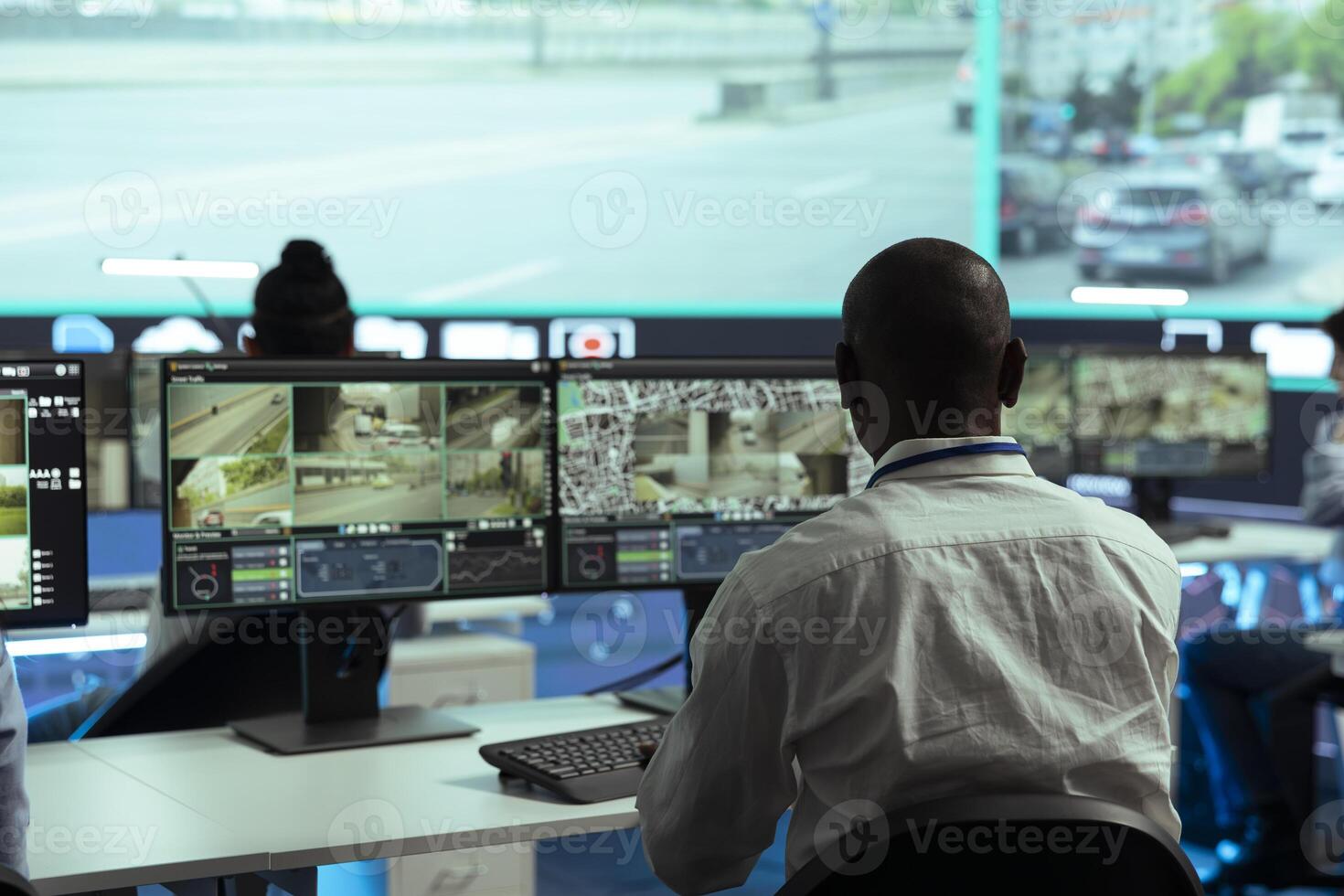 Observation room employee reviewing surveillance footage to find illegal activity within urban traffic, big screen. African american man collecting data via CCTV radar system. photo