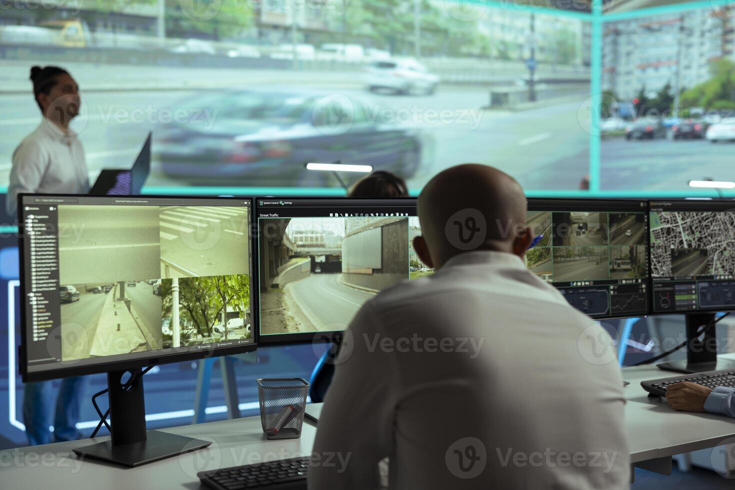 Middle eastern man overseeing the traffic surveillance footage on multiple displays, monitoring radar activity in an observation room. Team of people handling license plate reading on CCTV. photo