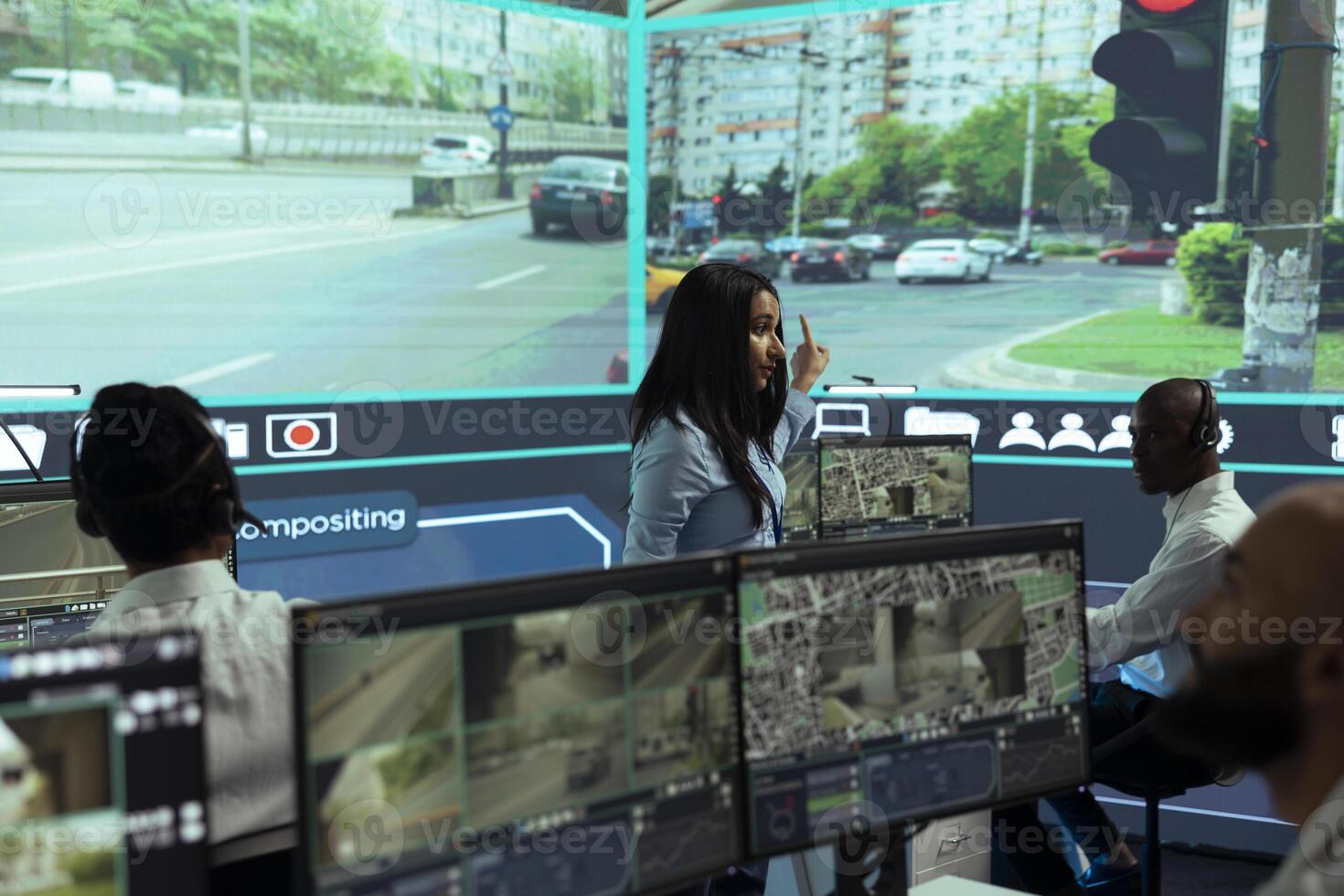 Indian woman team leader guides her staff to monitor surveillance footage in monitoring room, tracking speed limits for public safety via satellite CCTV system. Operates on screen in control center. photo