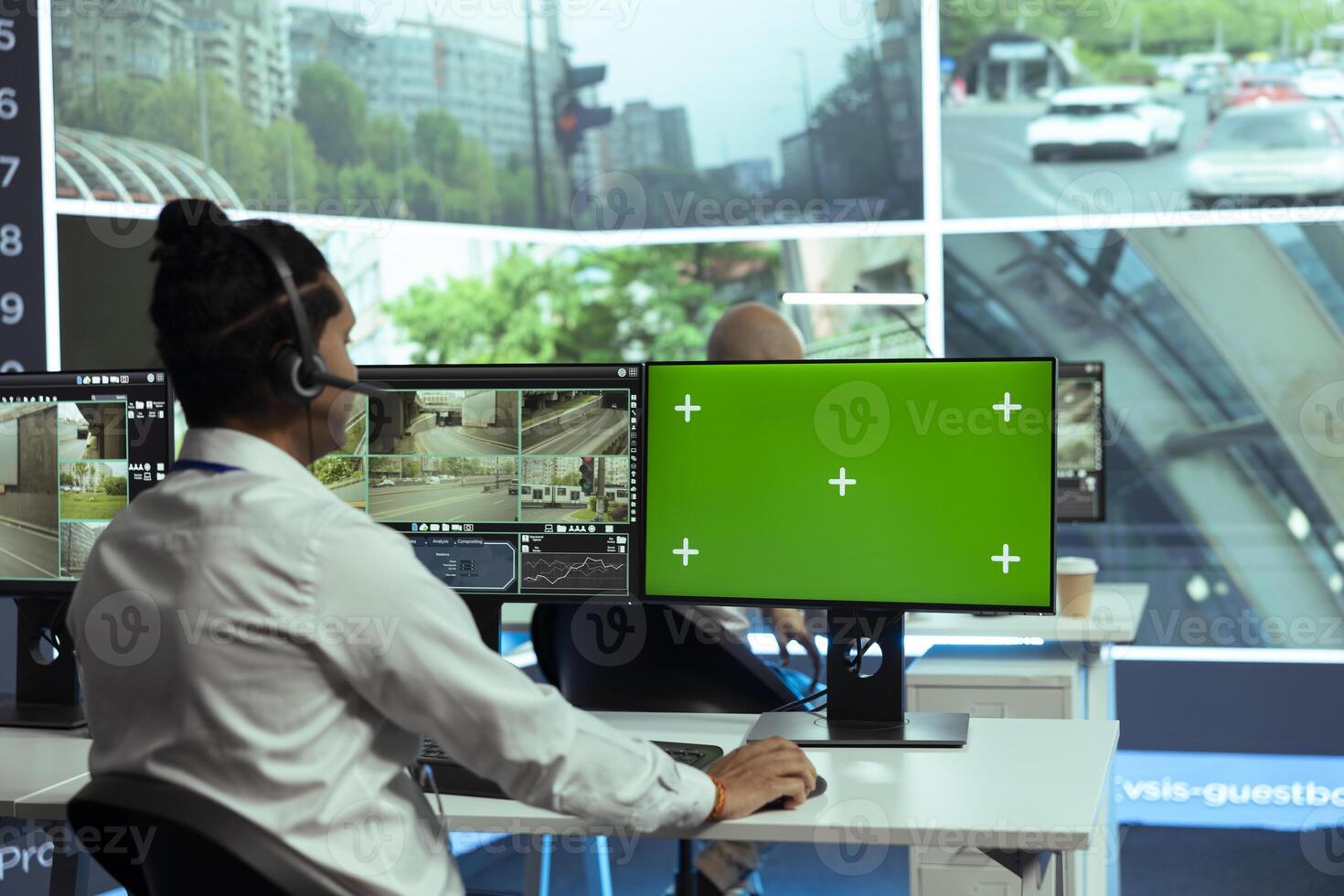 Indian specialist monitoring traffic surveillance next to a greenscreen display, gather intelligence on traffic activity in the city. Government employee collecting data on cars, plate recognition. photo