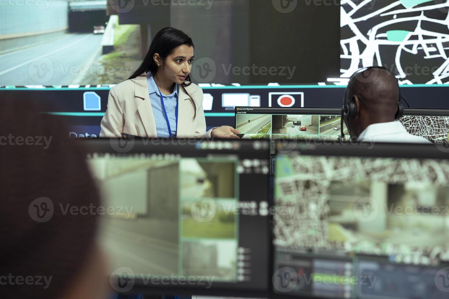 Indian supervisor gives instructions to her team in monitoring room, working on giving insight to truck drivers couriers about the best routes to avoid traffic. GPS tracking on satellite map. photo