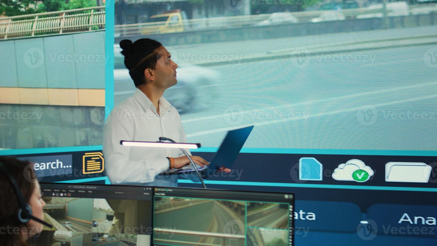 Indian man team leader coordinating his staff to observe urban surveillance footage through the CCTV security system. Government agency employees monitoring traffic via satellite cameras. Camera B. photo