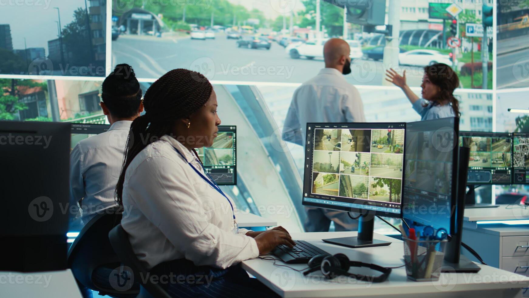 African american employee gathers data on cars in traffic through red light radar CCTV system, using real time surveillance footage for government safety activity. Camera B. photo