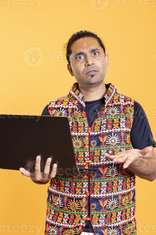 Portrait of man shocked after seeing error message on laptop screen while doing job tasks, studio background. Worker with perplexed facial expression, confused by mail received on notebook photo