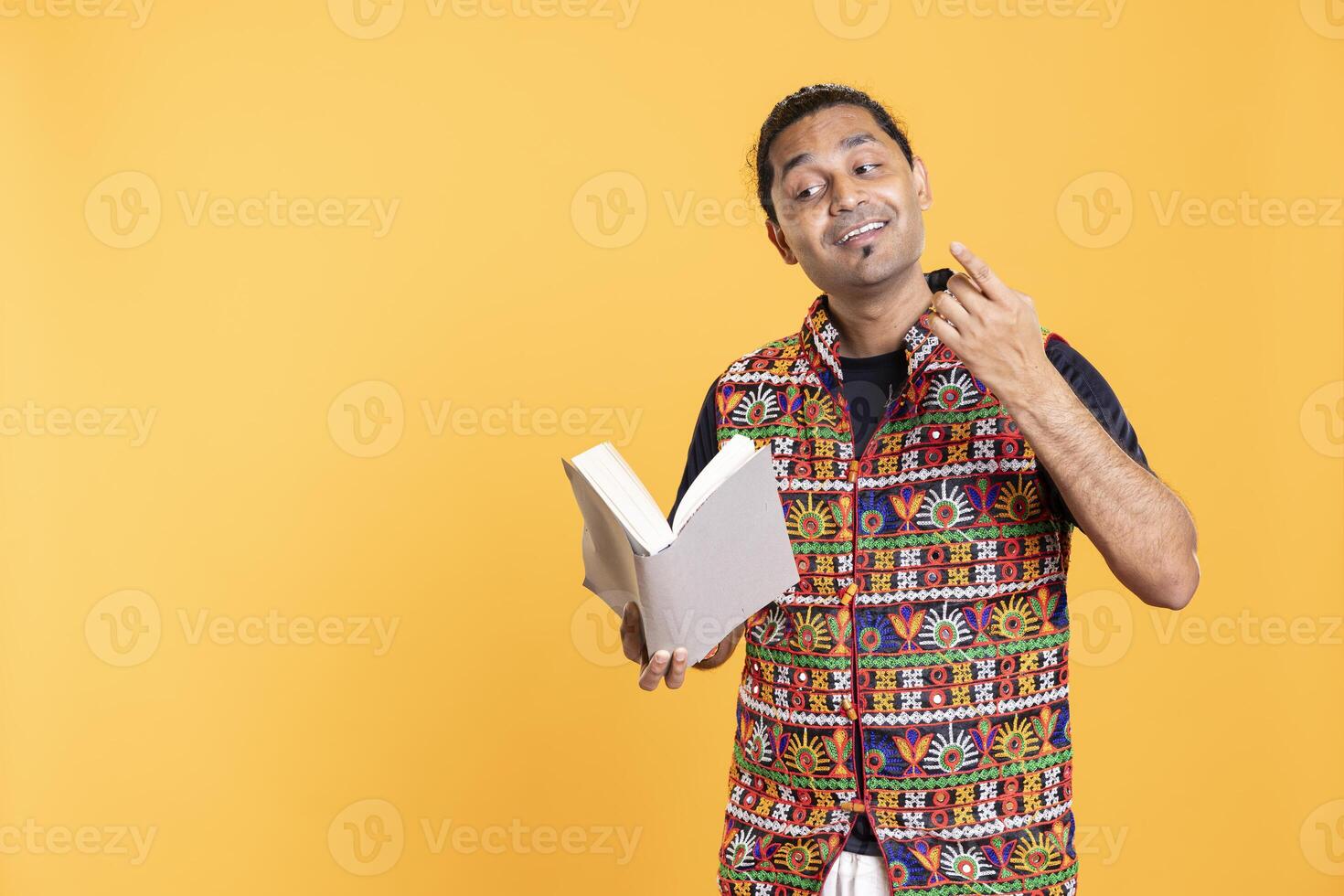 Indian man reading book aloud, narrating story for audience. Person enjoying literature novel, reciting from pages, entertaining spectators, isolated over studio background photo