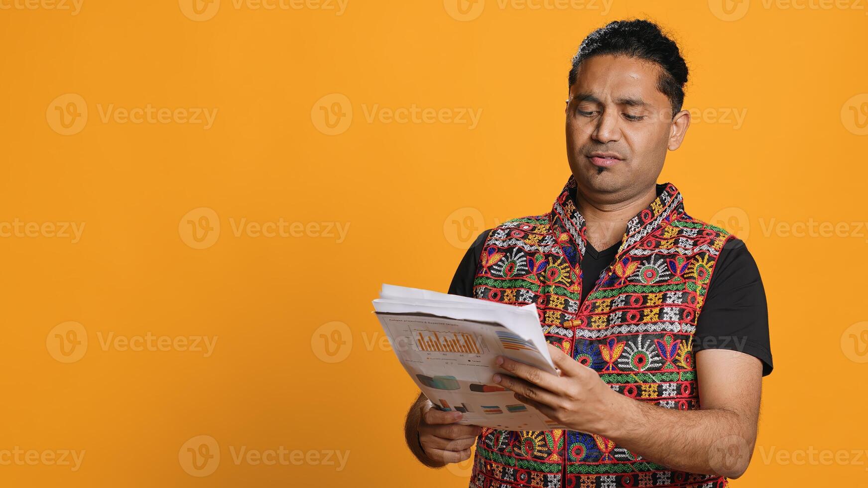 Irked manager looking over company financial profit report audit, disappointed by results, isolated over studio background. Mad indian man throwing business documents in frustration, camera A photo