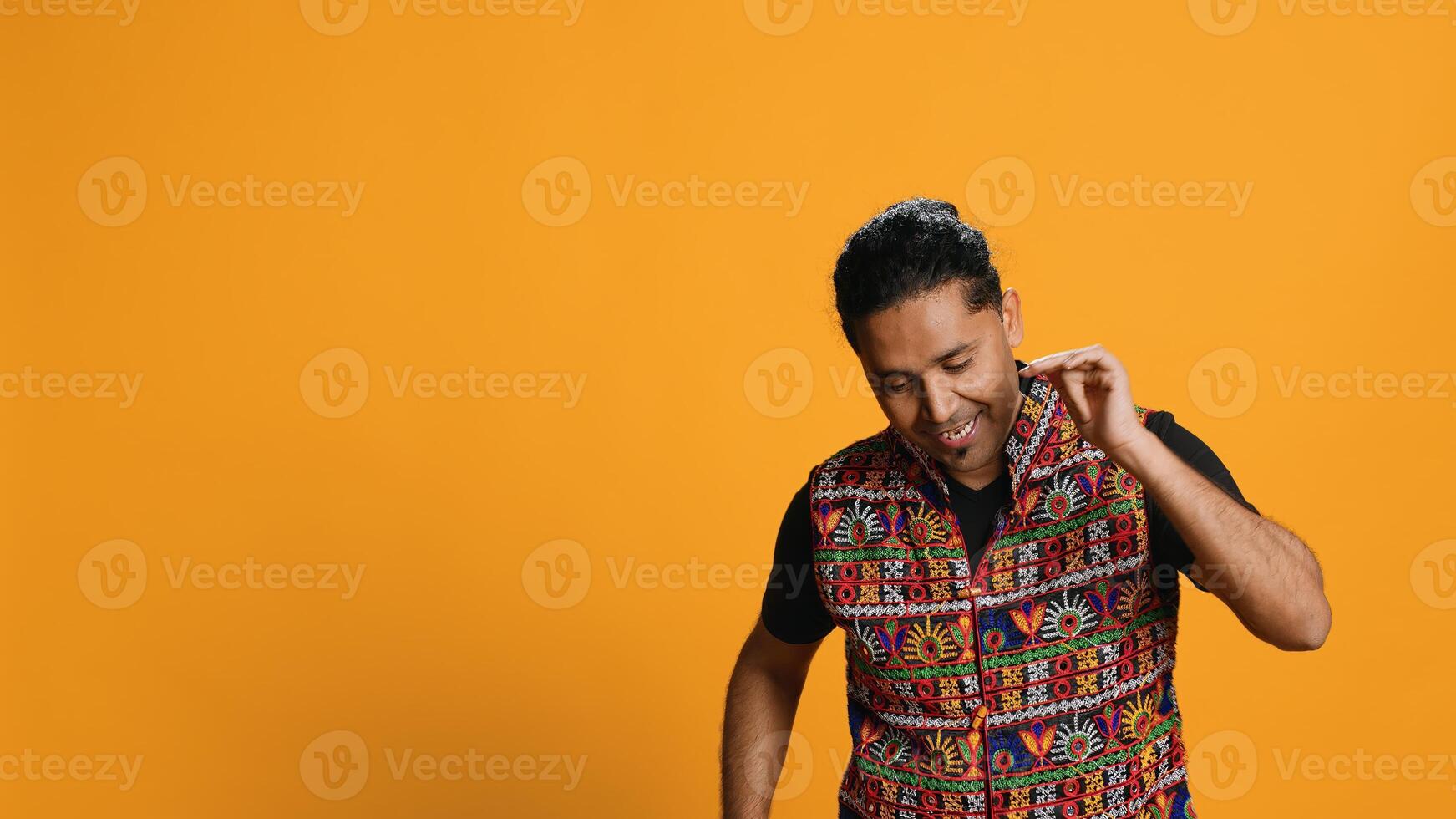 Smiling person having fun, dancing on rhythm, enjoying relaxation time. Jolly indian man goofing around, entertaining himself doing funky movements, isolated over studio background, camera A photo