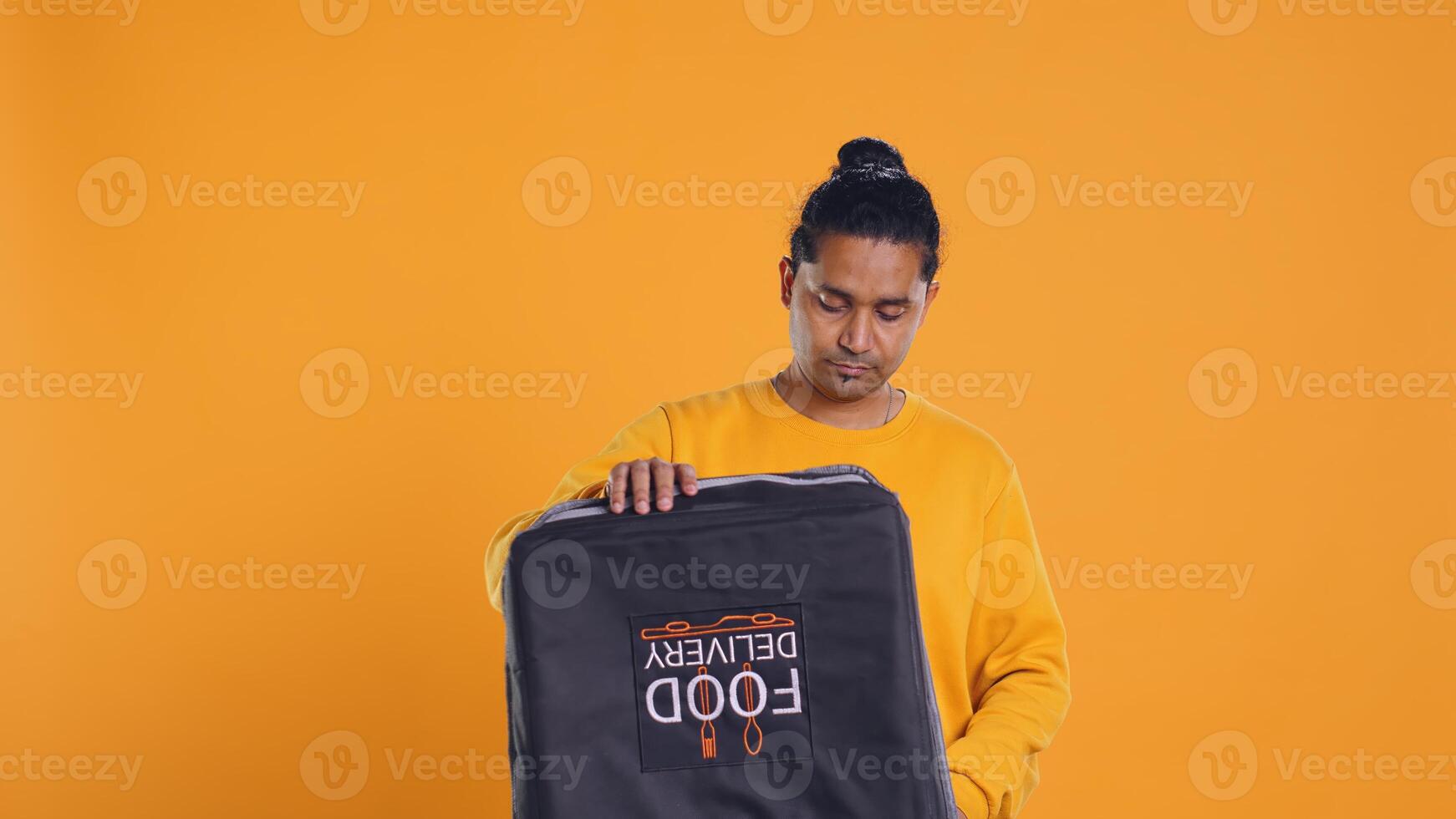 Delivery man doing face palm, shocked to see he displaced order in thermal backpack, throwing vegetables. Courier making mistake, packing incorrect groceries in bag, studio background, camera B photo