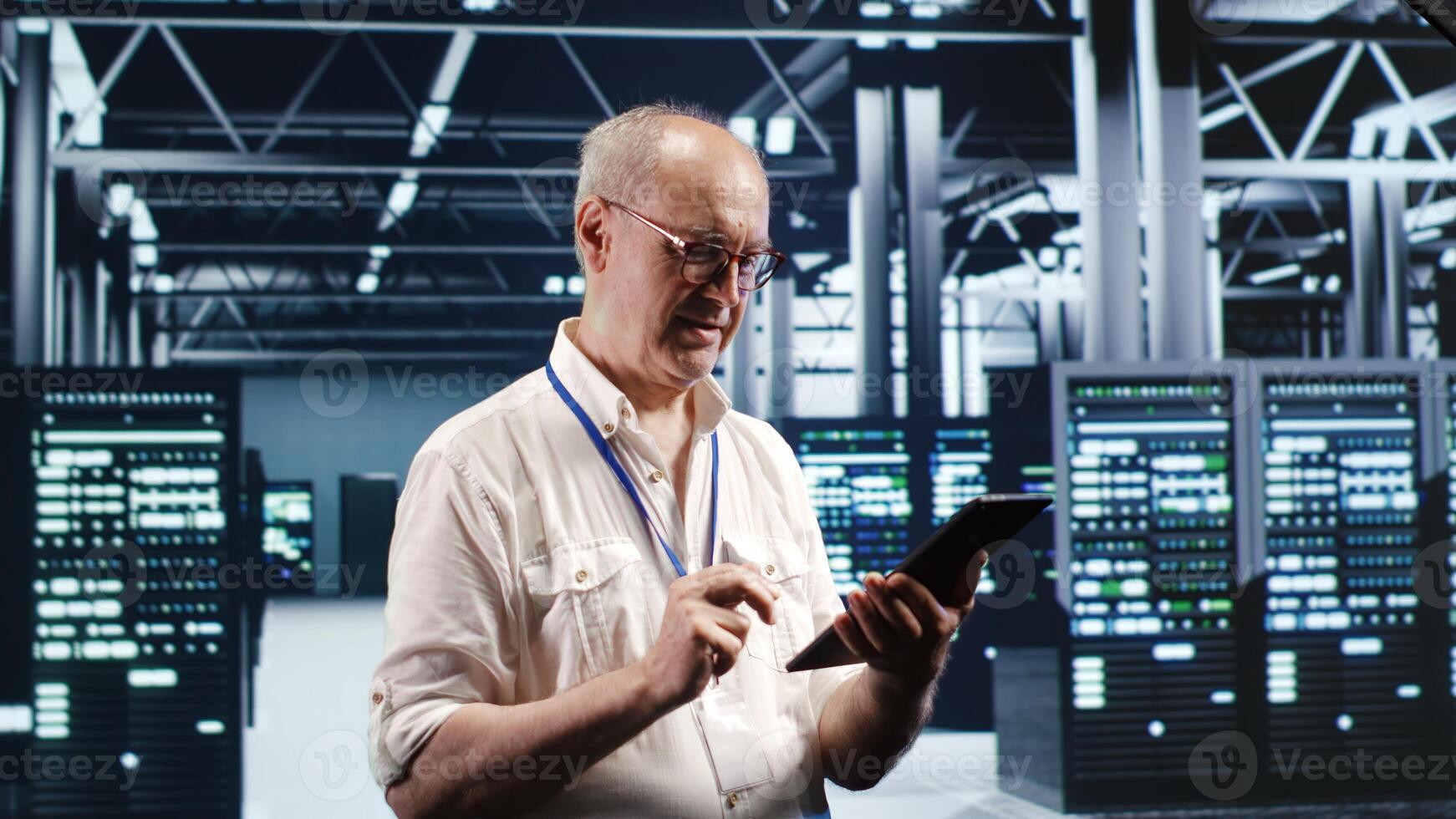 Octogenarian professional navigating network of server rigs in industrial base of operations. Admin with tablet doing review and optimizations in high tech data center, preventing system flaws photo