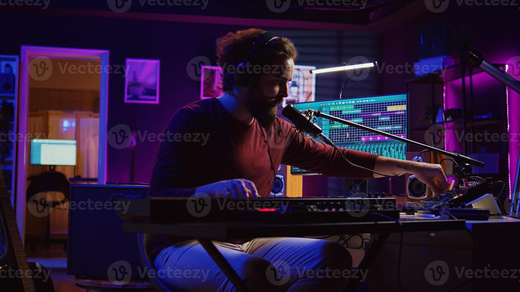 Sound engineer pressing keys of electric synthesizer and recording new music, adjusting noise level. Artist singing song on microphone, works with mixing board in home studio. Camera B. photo