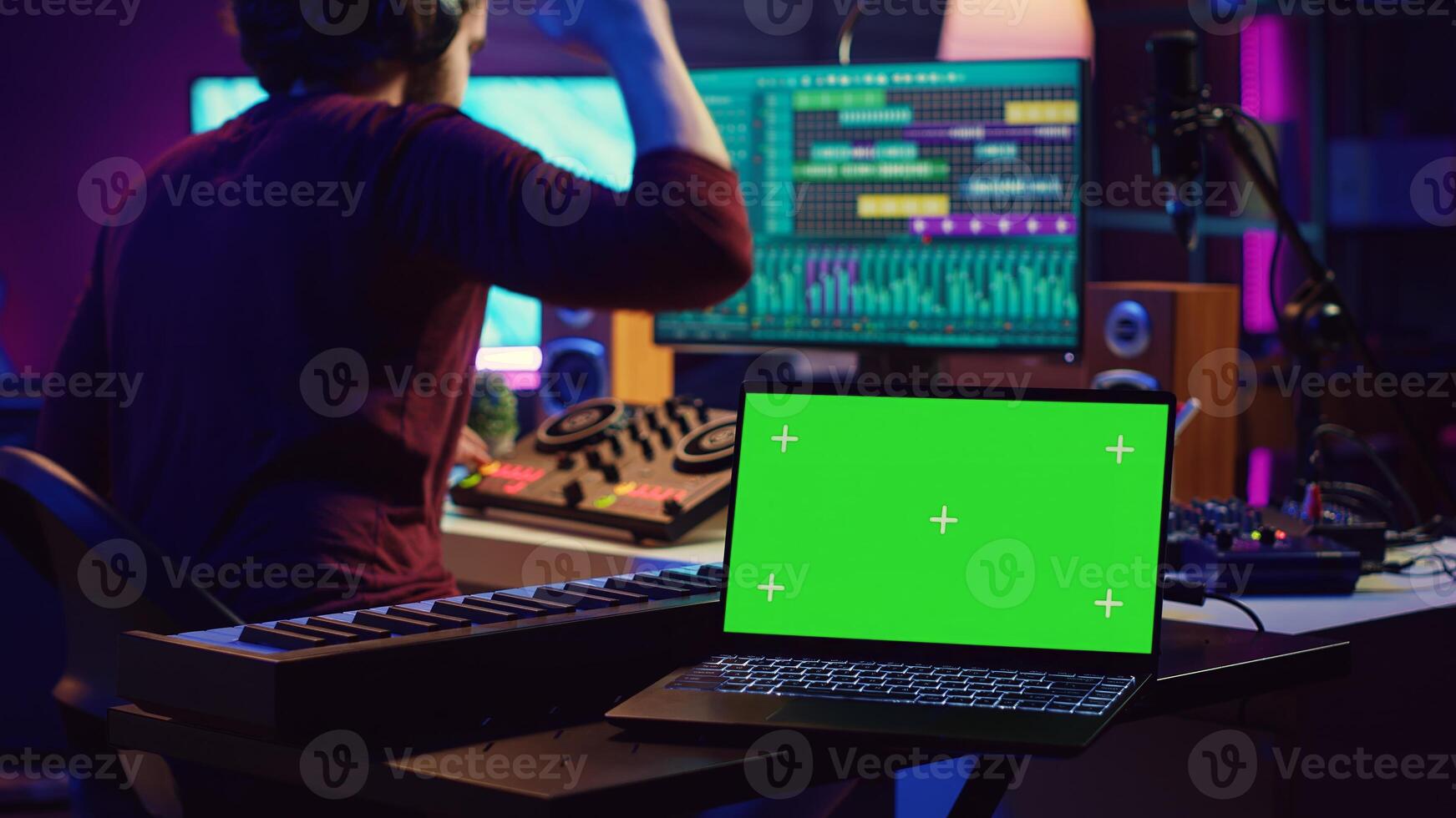 Music engineer editing audio recordings on mixing console and daw software, having a laptop with greenscreen in home studio. Artist producing a new song with acoustical engineering tools. Camera A. photo
