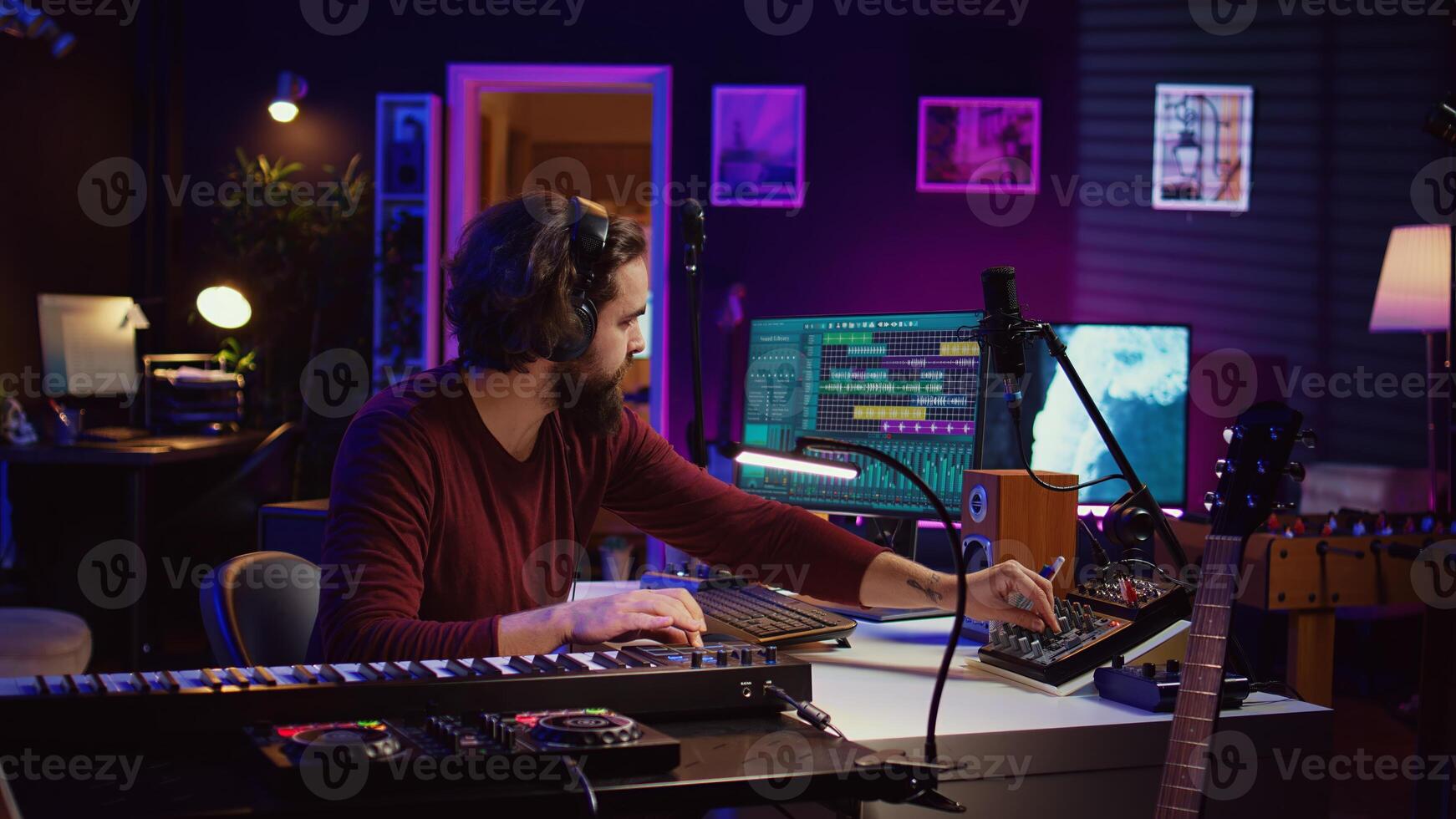 Sound engineer operates recording equipment and oversees audio performances to ensure the perfect notes. Musician composer producing sounds with MIDI controller and mixing console. Camera B. photo