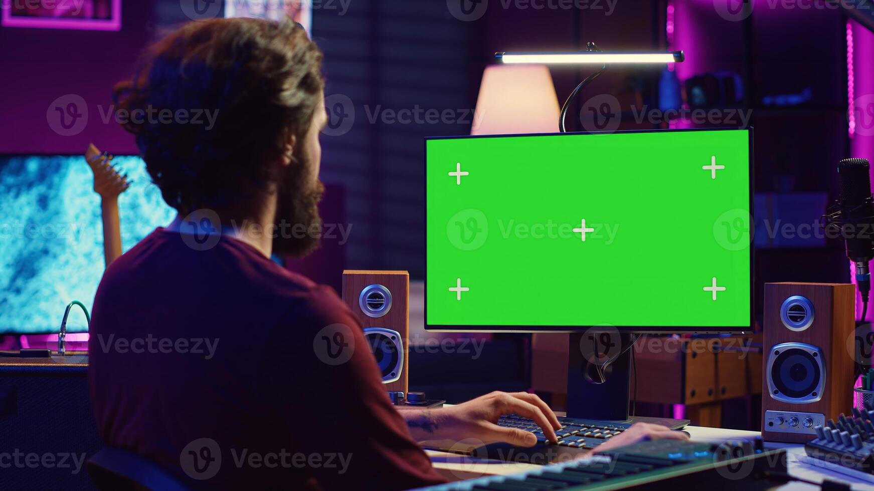 Music producer learning to use mixing console and soundboard, using online tutorial lesson on greenscreen. Artist learns to edit songs and add audio effects, mixing and mastering tracks. Camera A. photo