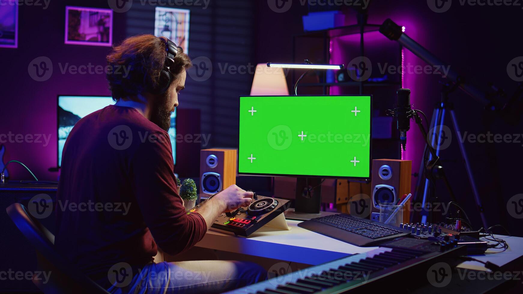 Music producer learning to use mixing console with online tutorial on computer, looking at isolated greenscreen display. Sound engineer practices editing sounds in his home studio. Camera B. photo