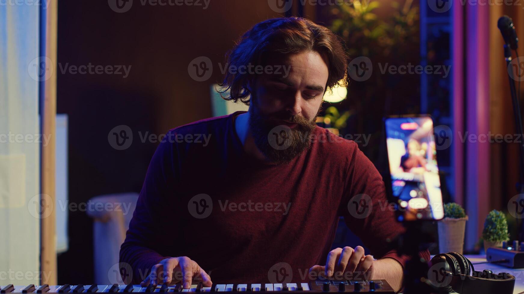 Artist teaching online piano lessons from his home studio, recording tutorial and playing midi controller synthesizer. Instructor explaining electronic keyboard notes, music industry. Camera A. photo