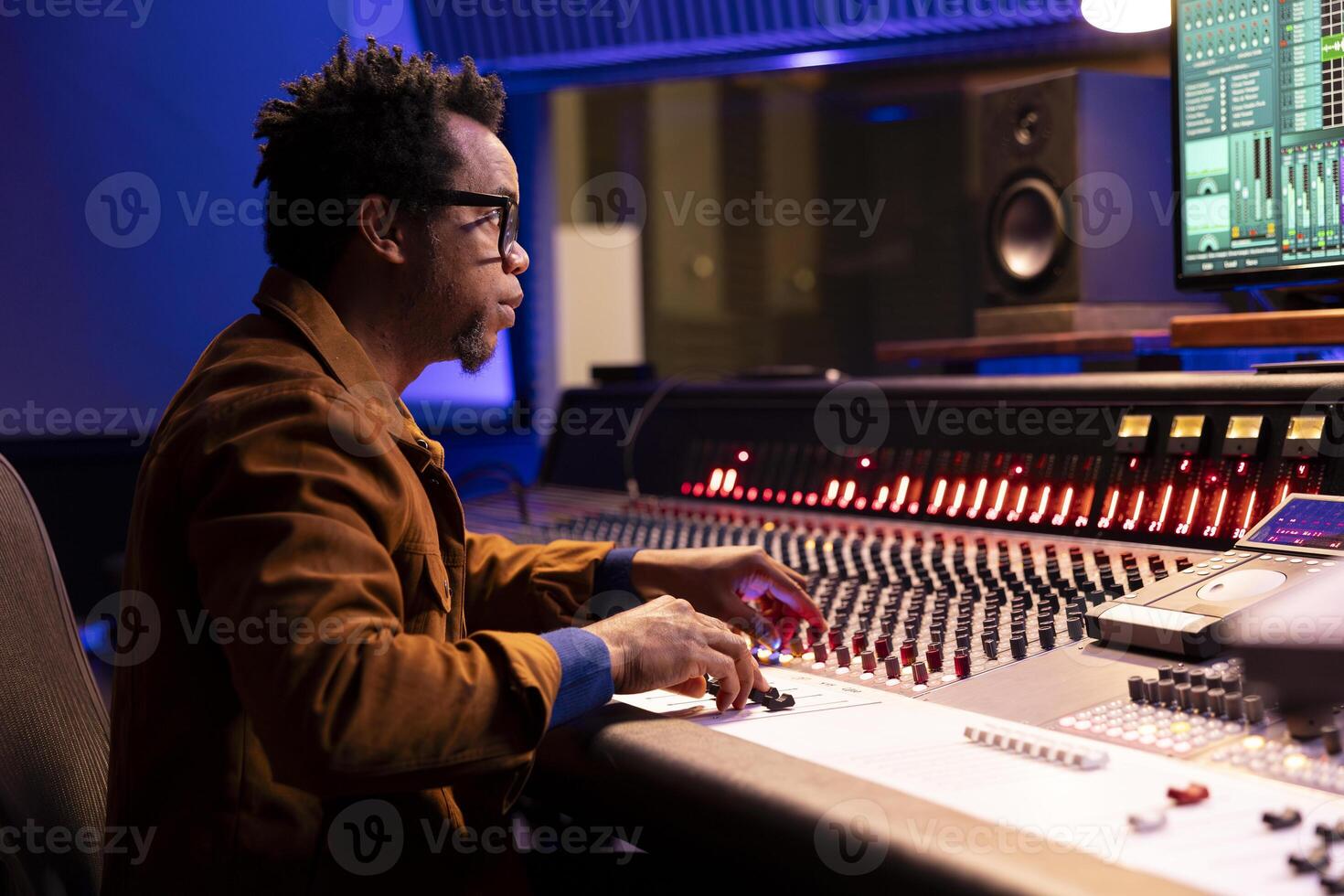African american sound designer uses control desk with automatic equalizer, mixer and faders to edit music in post production. Audio expert processing audio recordings, mixing console. photo