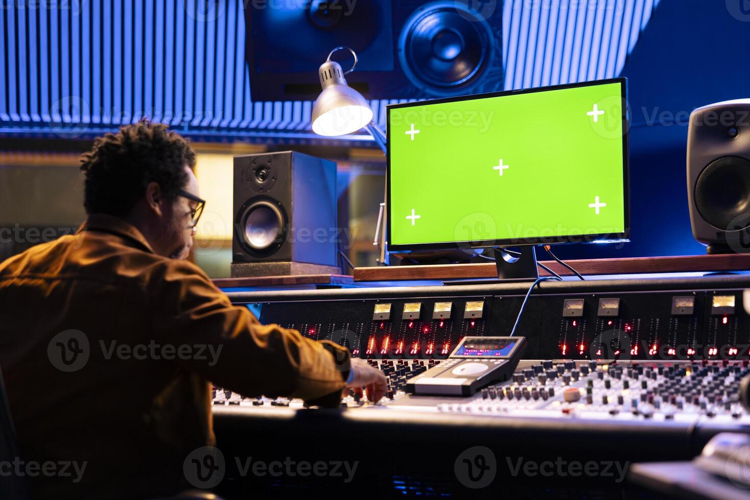 Audio technician uses computer with isolated layout and control panel board, professional music studio. Producer recording tracks and editing with sliders or buttons, control room gear. photo