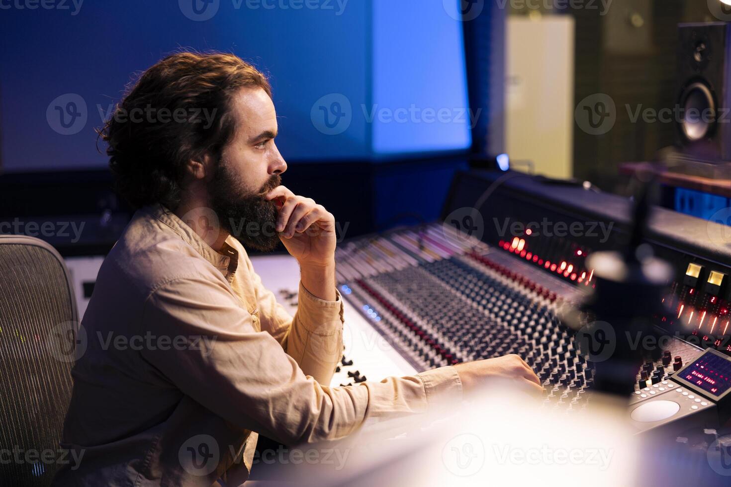 Music producer editing tracks with mixing console and faders, operating control desk to remove tonal imbalances or white noise. Sound designer twists knobs, adjusting volume on recording. photo