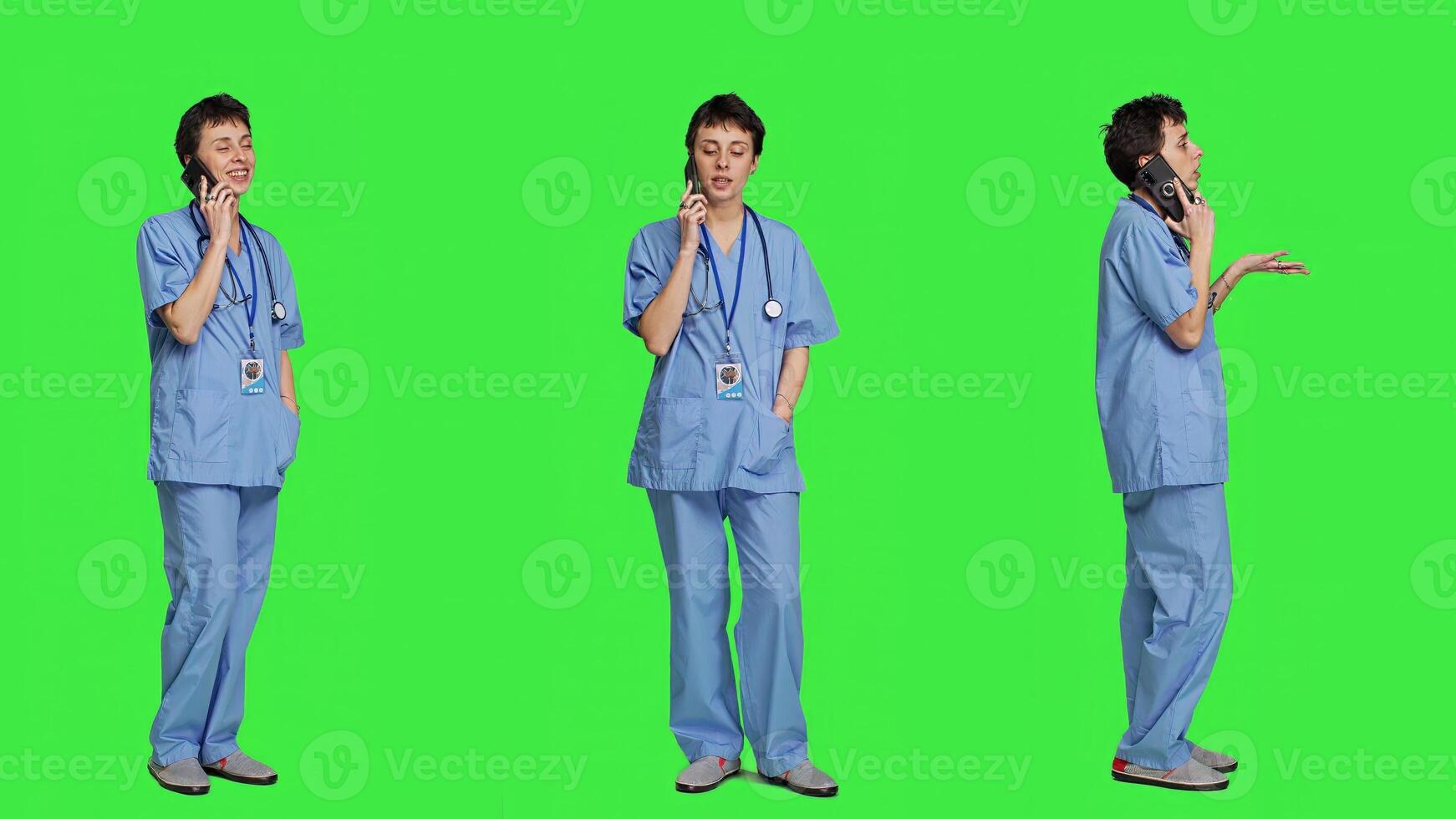 Health specialist using smartphone to make important calls, standing against greenscreen backdrop. Nurse talking to patients for checkup exams on telephone line, calling people to confirm. Camera A. photo