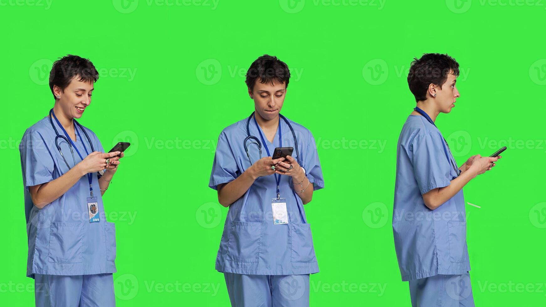 Young nurse texting on smartphone against greenscreen backdrop, using mobile phone to check social media messages on work break. Medical assistant browsing online web pages. Camera B. photo
