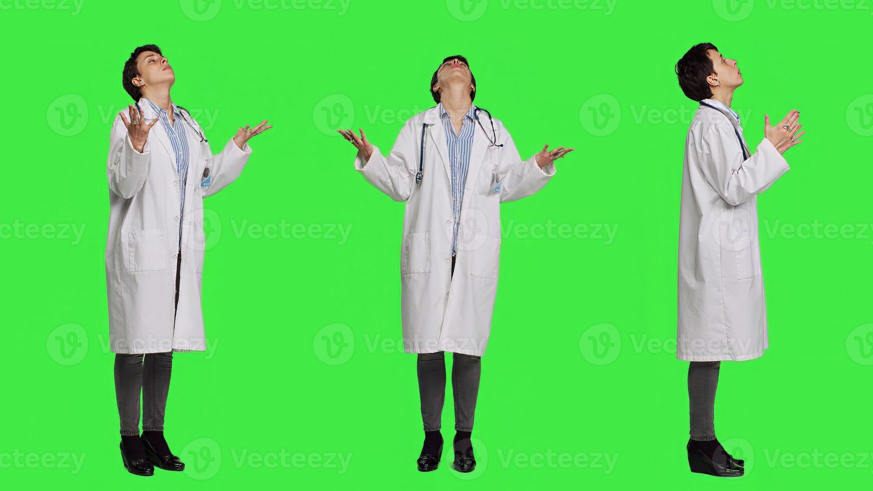 Religious woman physician praying to jesus christ against greenscreen, looking up and saying a prayer. Doctor worshipping God and meditating, spiritual medic with belief in christianity. Camera A. photo