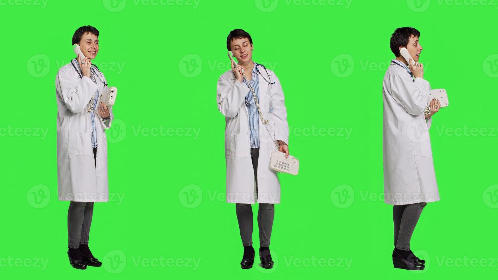 Physician answering landline phone call against greenscreen backdrop, talking to patients about checkup appointments. Medic having remote discussion on retro telephone with cord. Camera A. photo